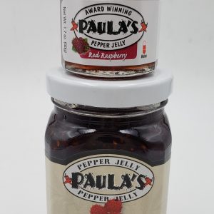 1.7 oz. Paula’s Pepper Jelly jar on top of the 8 oz. Paula’s Red japantube Pepper Jelly jar. Both are label out and full of pepper jelly.